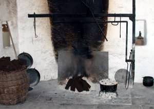 Peat sods on open hearth in wide chimney space, fire-making and cooking equipment